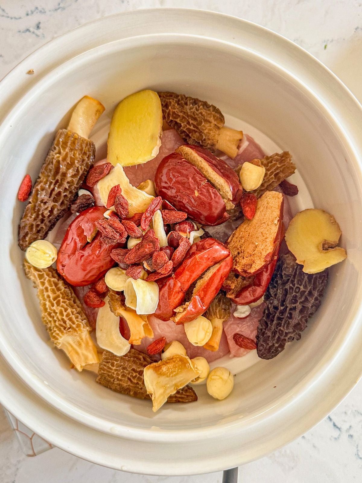 A pot with mushrooms, jujube, goji berries, ginger, and Chinese herbs.