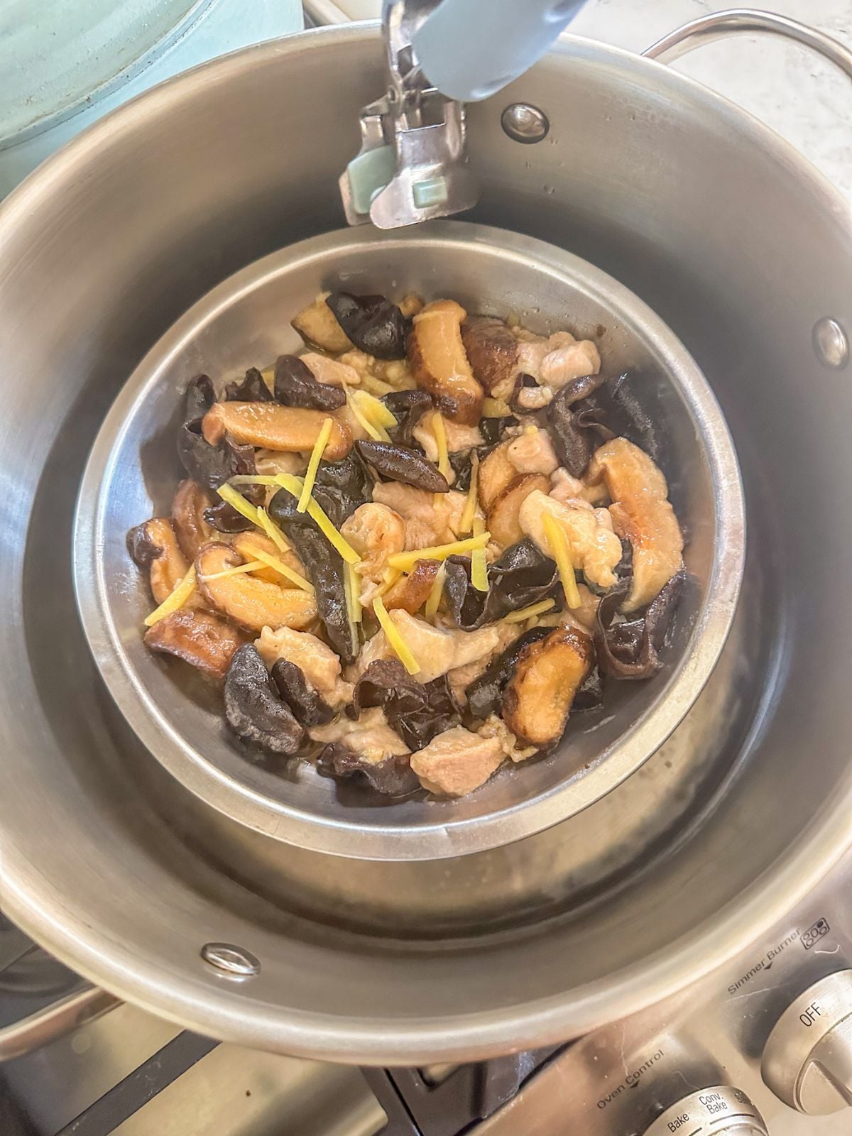 Placing a bowl of marinated chicken onto a steaming rack inside a pot filled with water.