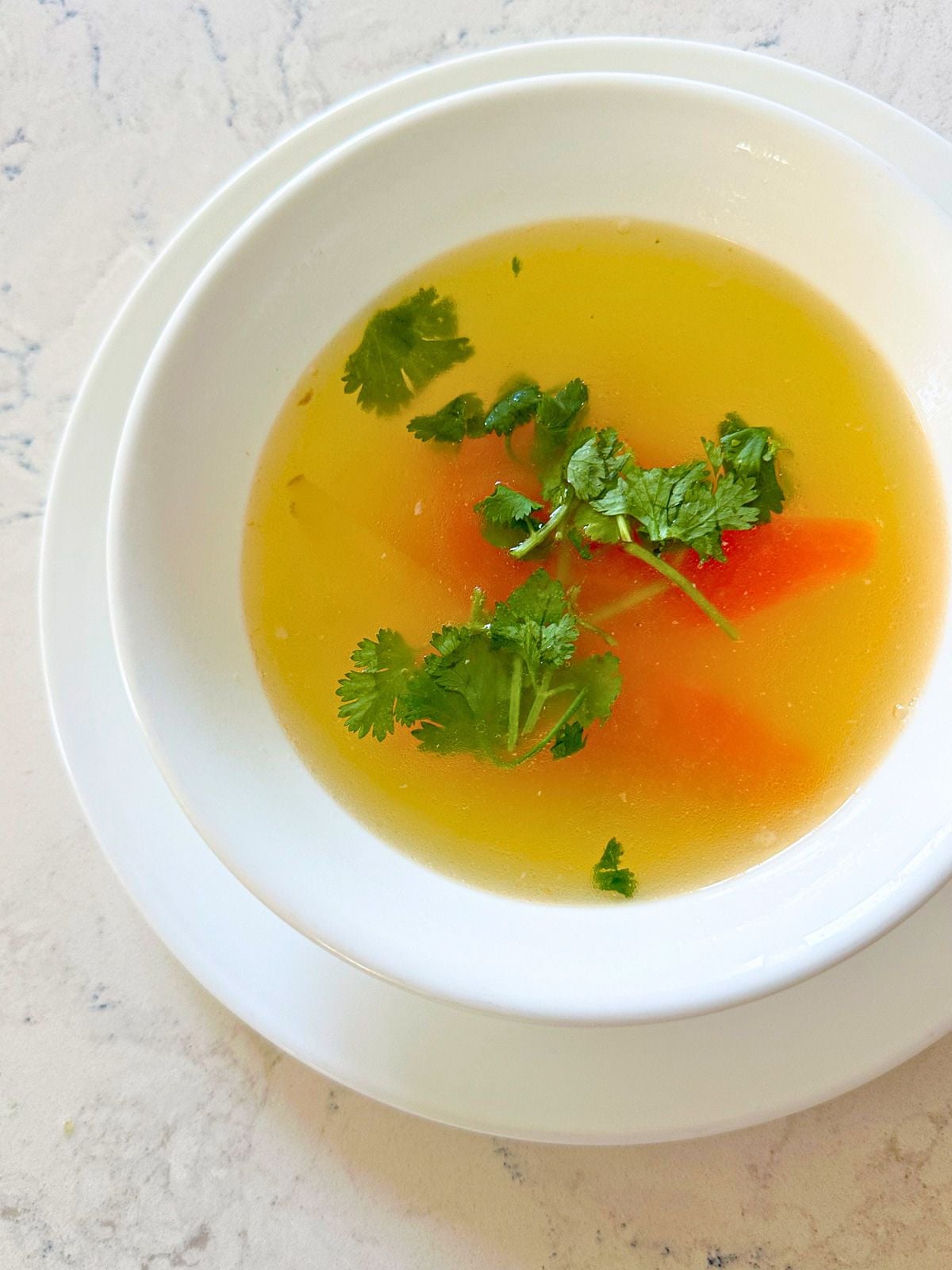 A bowl of soup with papaya, garnished with fresh cilantro.