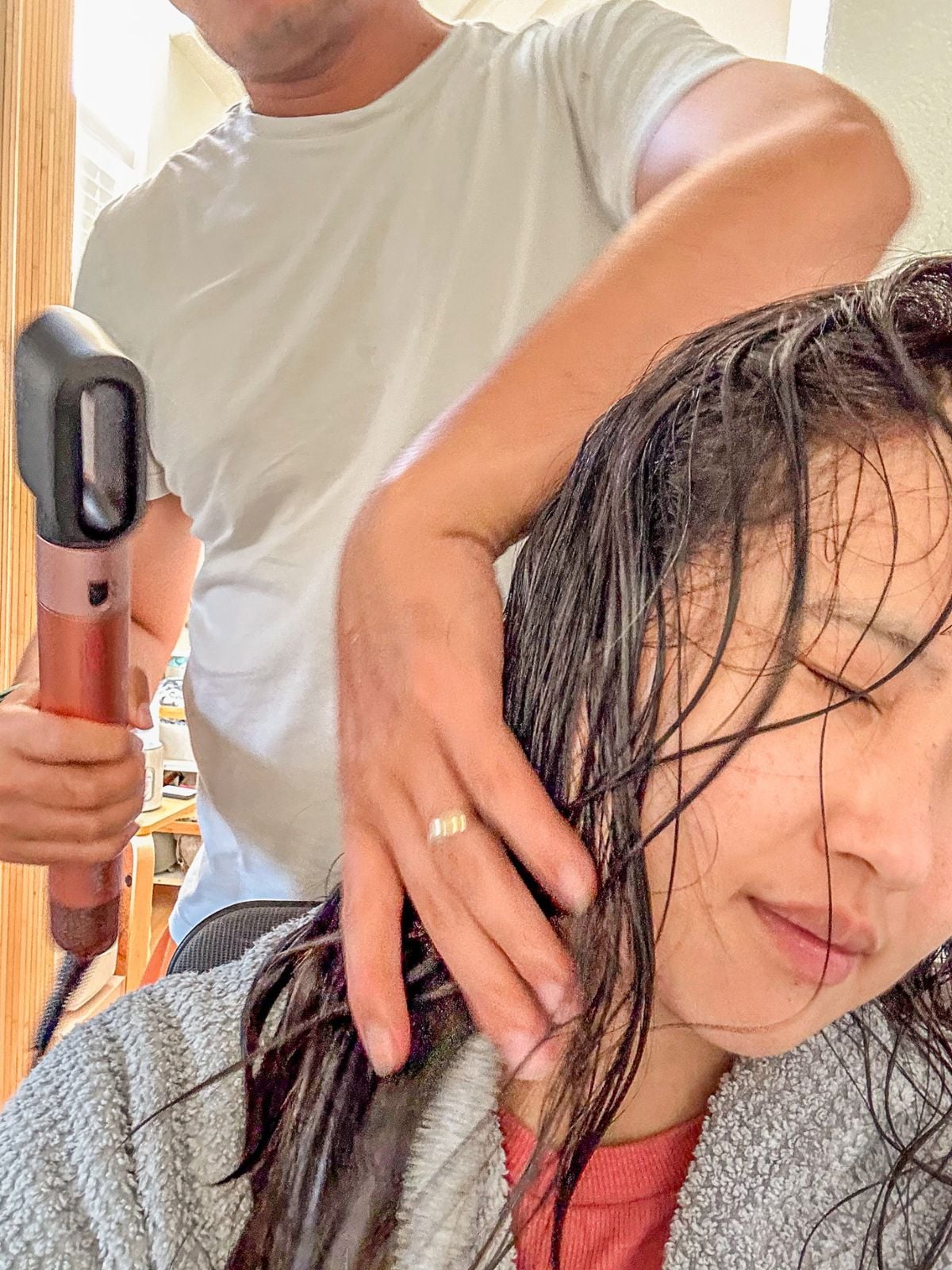 A man using a hair dryer to dry a girl's wet hair.